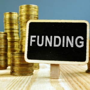 Coins to the left of a tabletop chalkboard that reads - 