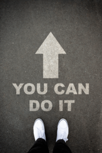 A person standing on a road with the words you can do it written on it